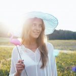Beauty Smiling Girl on the Spring Field. Meadow. Portrait of Laughing And Happy young model woman with healthy long blowing hair Enjoying Nature. Beautiful Young Woman Outdoors in Slow Motion